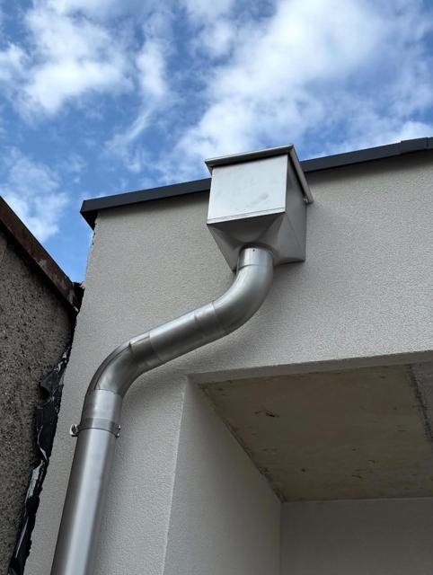 Wasserkasten mit Ablaufrohr aus Zinkblech an Hausfassade